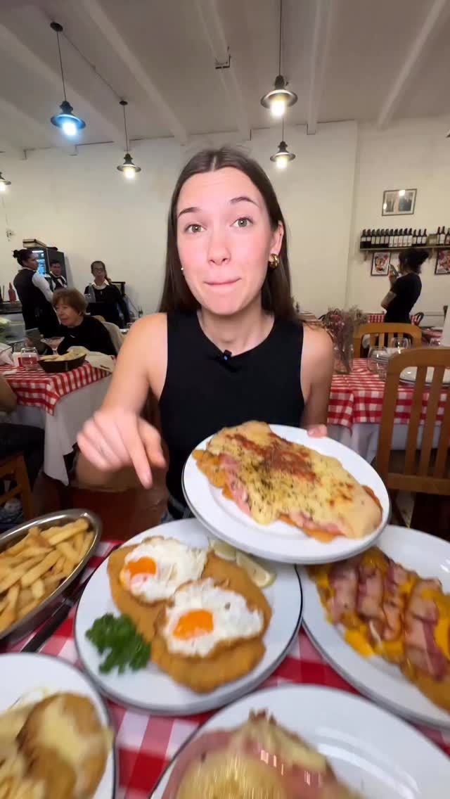 Comensal mostrando una milanesa abundante en el salón del bodegón