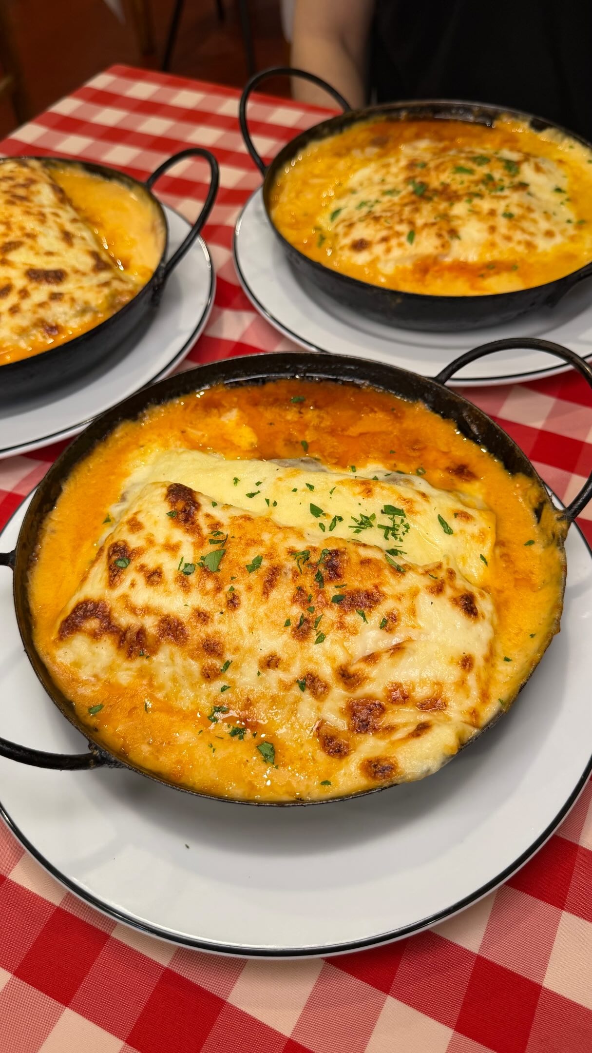 Lasagna gratinada servida en cazuela sobre mantel de cuadros